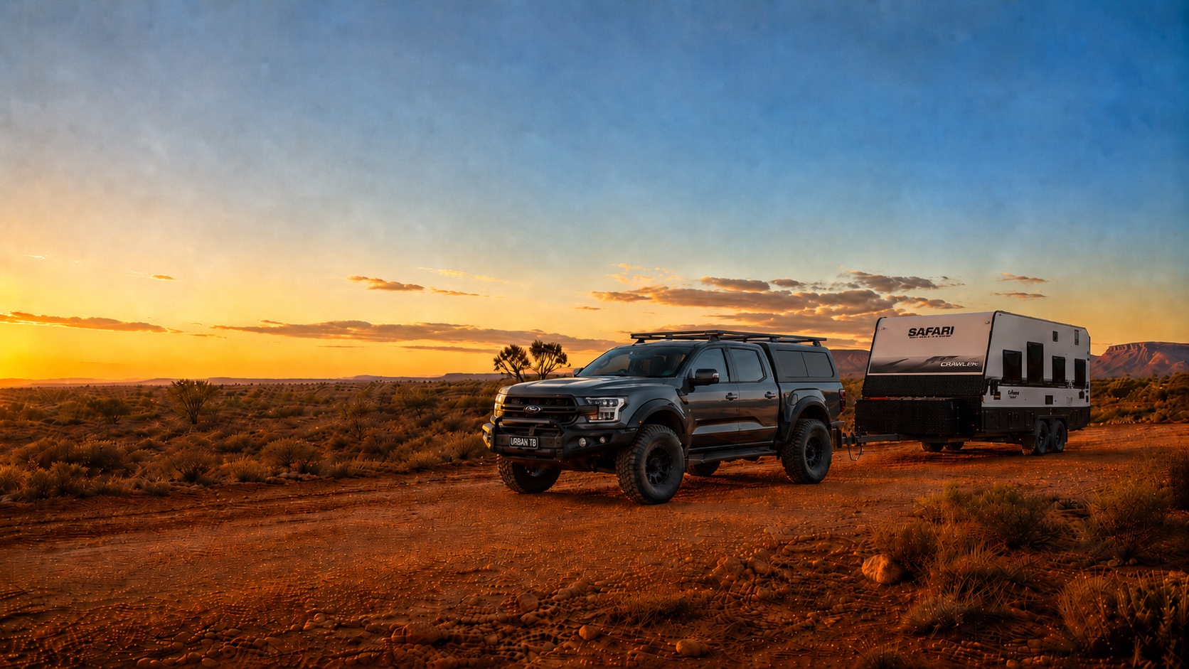 Dual-cab ute fitted with a black aluminium canopy and tray, hitched to an off-road caravan on a red outback dirt road at sunset